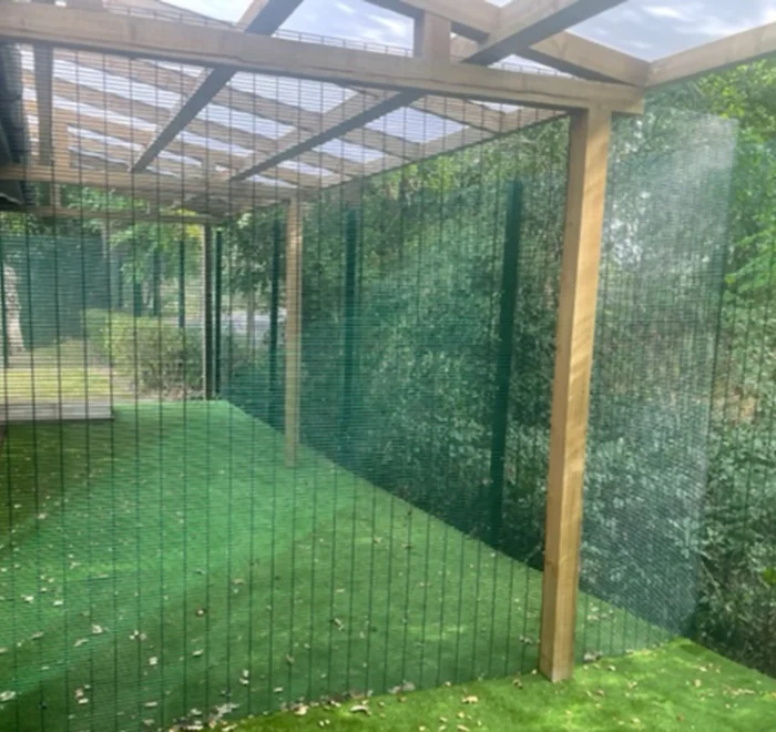 Covered outdoor space with a timber shelter and mesh fencing at Starlings